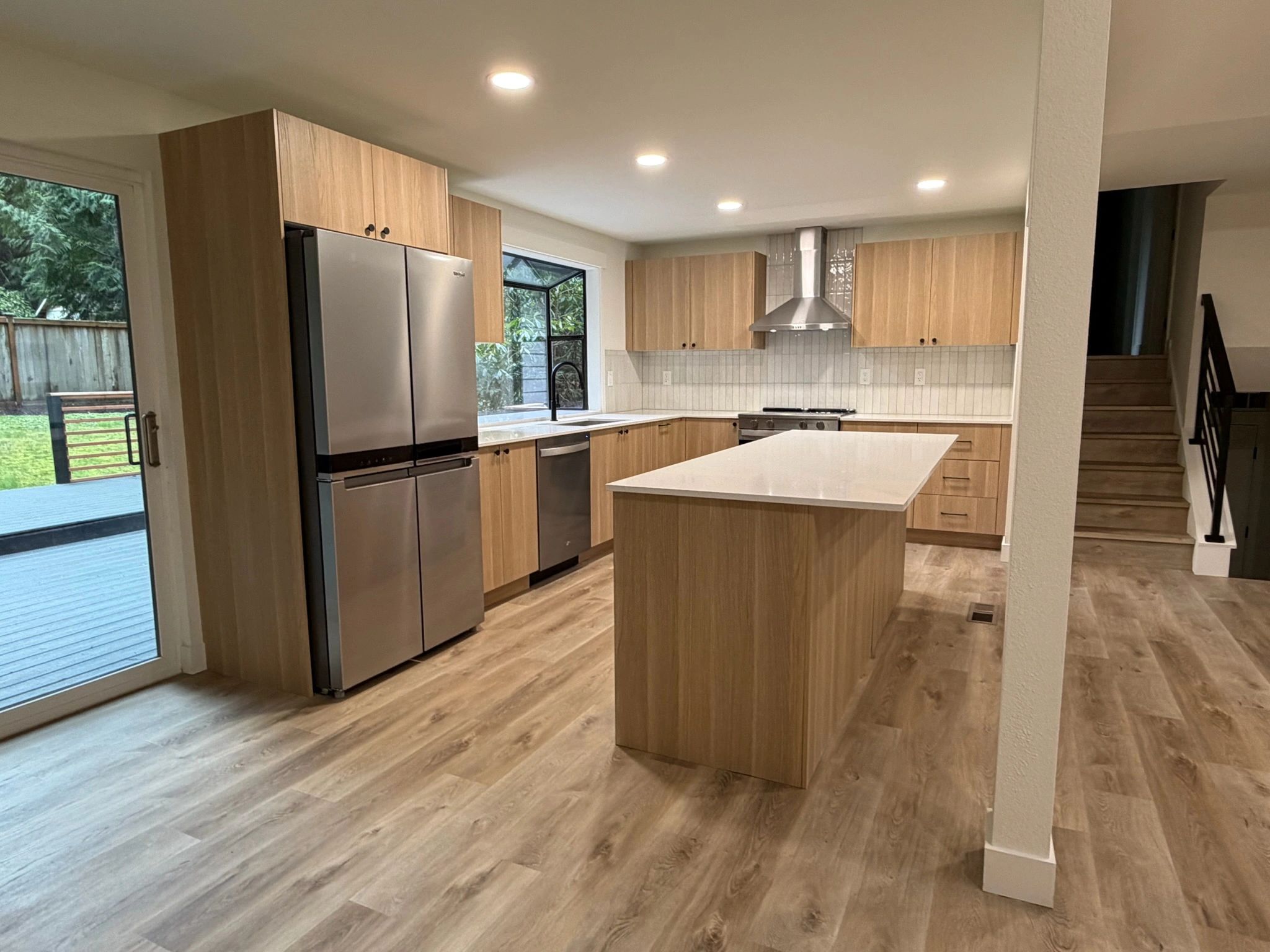 Remodeled kitchen with light wood cabinets and a large island