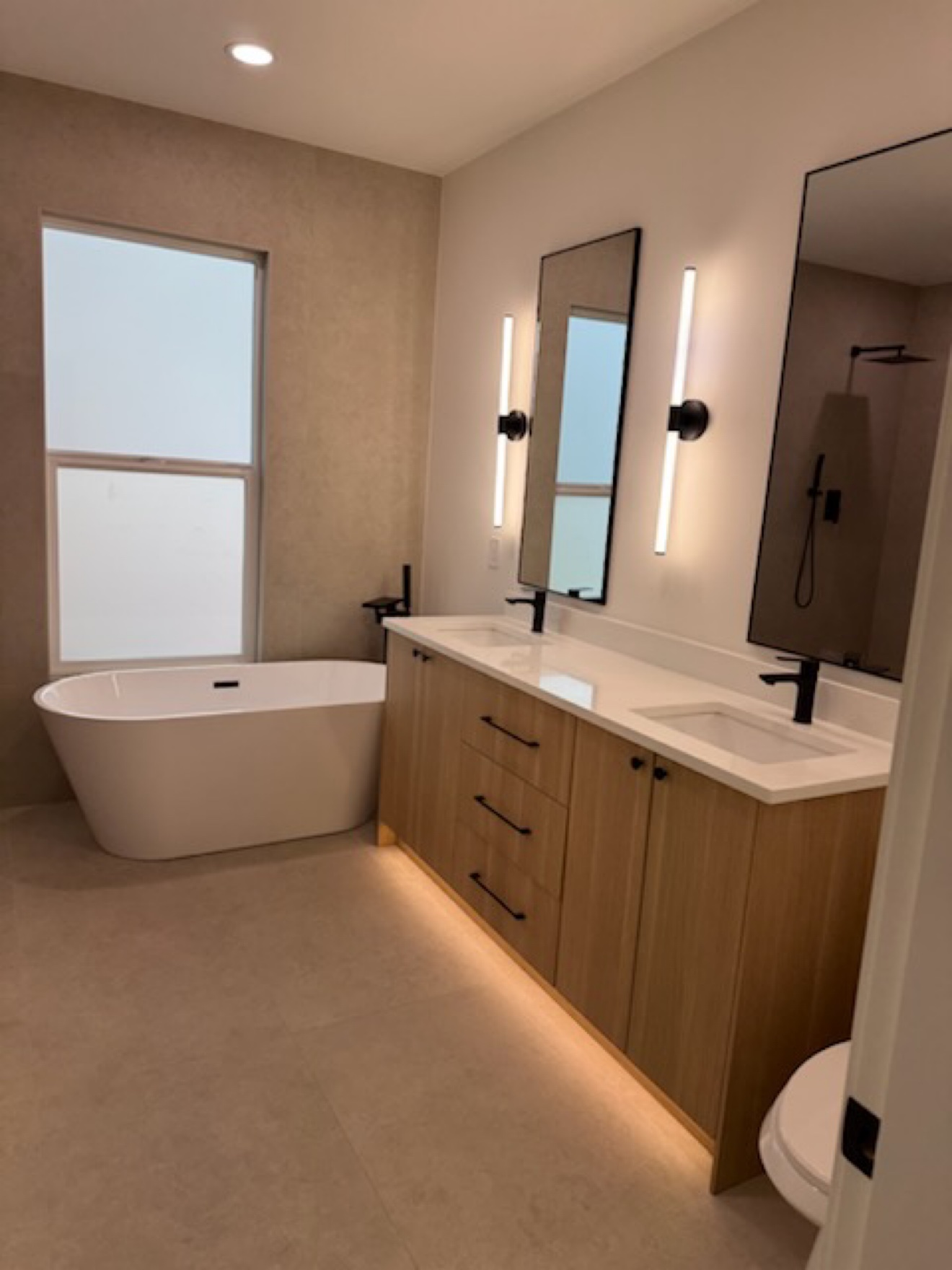 Bathroom with freestanding tub, long double vanity and vertical sconces